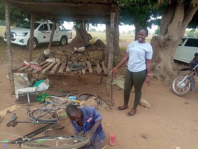 Joseph with Opportunity Bank Uganda's financial inclusion officer working by his workshop repairing a bike