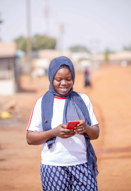 Imoro - a digital financial services client - uses her mobile phone for business in the marketplace.